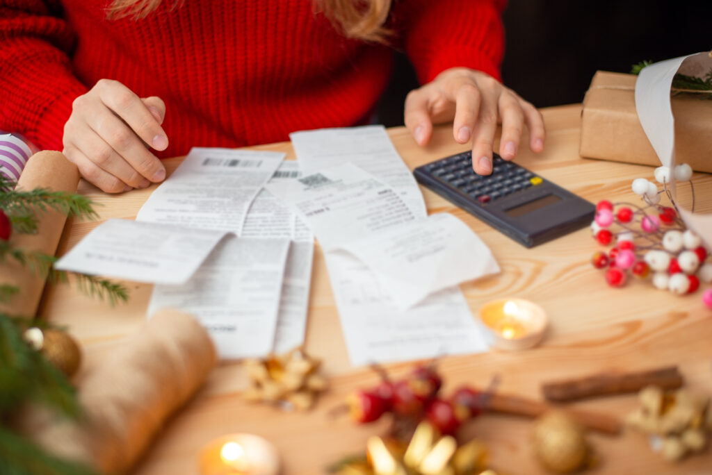 Close-up shot of checks, bills and receipts on wooden table and girl counting them. Concept of much spends on Christmas holidays celebration, money on presents and decorations - Bloom Analytics